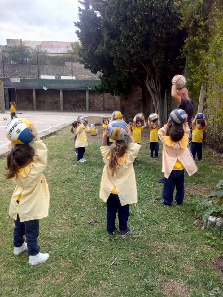 Niñas y niños jugando con pelotas durante una clase de educación física
