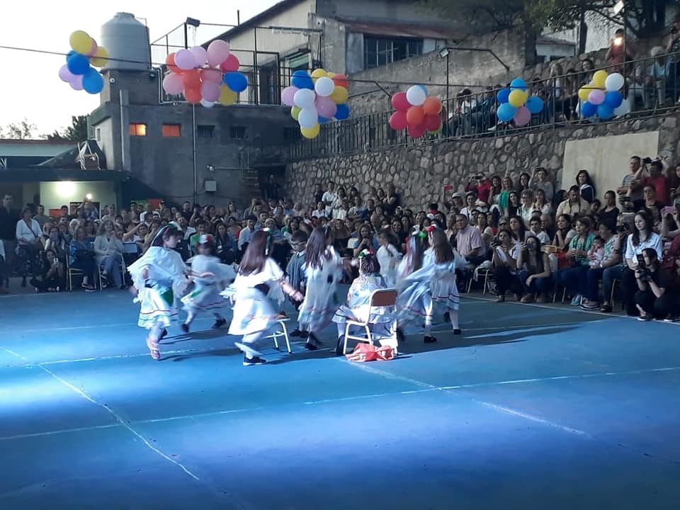 Estudiantes bailando ante sus familias durante un acto escolar