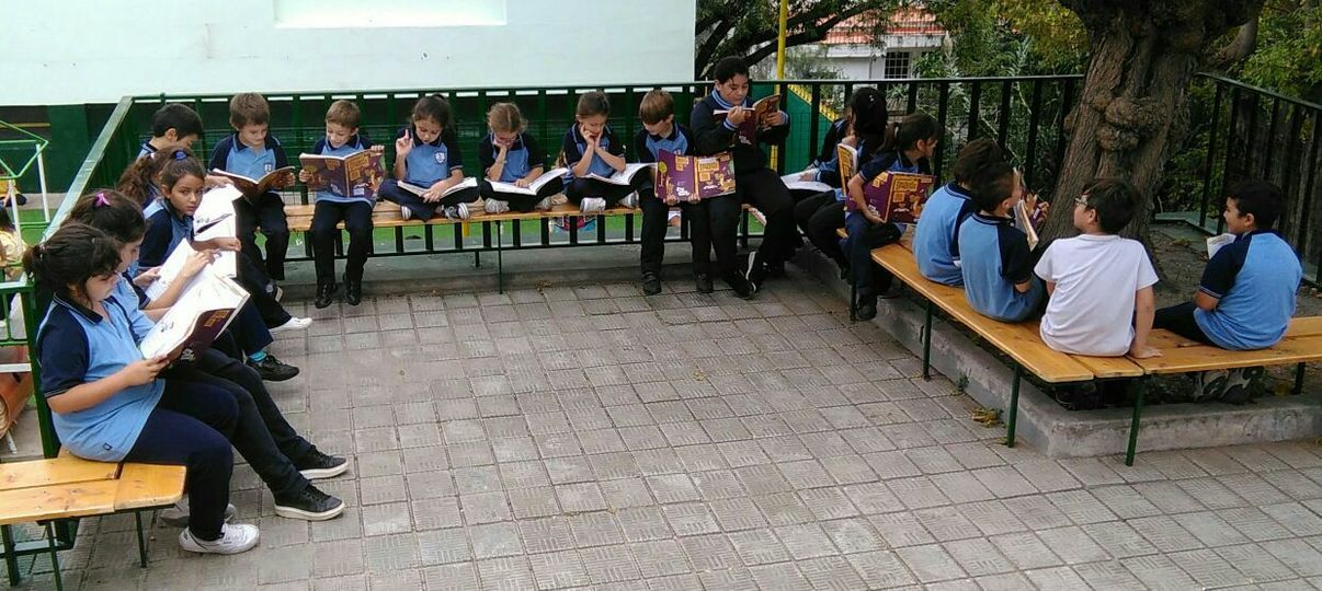 Estudiantes de nivel primario leyendo al aire libre